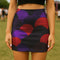 A woman wearing a short skirt with a colorful, abstract pattern of circles and lines in shades of purple, red, and black.